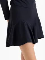 Pollera mini negra de corte ajustado con ruedo acampanado y detalle de volados en la parte inferior.