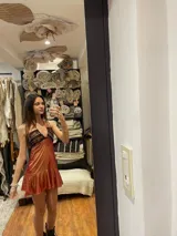 Vestido corto negro con diseño cut-out en la cintura y detalle de encaje en el centro del busto. Presenta breteles finos, falda con volado en el ruedo y flecos decorativos.