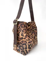 Bolso tipo hobo de tela con estampado animal print, con correa de cuero marrón ajustable con hebilla.