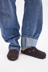 Zueco de cuero vacuno en color marrón oscuro, con diseño de punta cerrada, ajuste mediante hebilla metálica lateral y suela de corcho con base de goma.