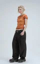 Remera de manga corta y cuello redondo, confeccionada en tejido ribb 100% algodón, de calce ajustado al cuerpo y largo a la cadera. El color es un marrón oscuro con efecto desgastado o teñido. Presenta costuras externas visibles en los hombros y laterales.