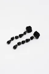 Pendientes largos de diseño colgante, compuestos por una pieza superior en forma de rosa y una serie de elementos en forma de gota, todos con acabado aterciopelado negro.
