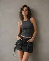Mini falda tipo cargo de denim negro con efecto lavado, tiro bajo, bolsillos frontales tipo cargo con solapa y detalle de tiras laterales colgantes.