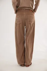 Pantalón de pana de corte ancho y tiro medio-bajo, con diseño de cinco bolsillos y acabado lavado. Presenta un aplique cuadrado decorativo en una de las piernas y un pin bordado de la marca.