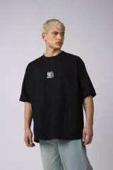 Remera negra de corte oversize con cuello redondo y estampa frontal pequeña con el texto 90's en color blanco.