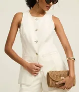 Chaleco largo color crudo confeccionado en sarga de algodón, con cuello redondo, cierre abotonado, bolsillos delanteros y cintura ajustada.