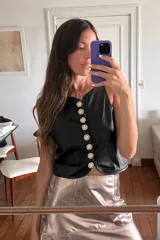 Chaleco negro de cuero ovino con botones de strass y cuello redondo.