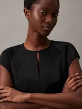 Blusa negra de satén brillante con cuello redondo y mangas cortas.