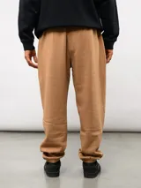 Pantalón jogger de felpa color negro, con cintura elástica, puños en los tobillos y etiqueta con el logo de la marca en la parte frontal.