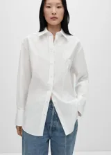 Camisa de corte oversize confeccionada en tejido popelín de mezcla de algodón y lyocell. Presenta diseño recto, cuello camisero, cierre frontal con botones y manga larga con puños abotonados. Incluye un sutil detalle bordado en el pecho.