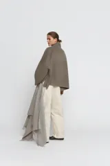 Cazadora de corte amplio confeccionada en hilatura con lana, color beige. Presenta cuello subido, manga larga y cierre frontal con botones negros. Destaca por sus acabados con costuras de hilo a contraste en los bordes.