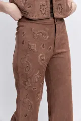 Pantalon de gamuza sintética color marrón, de corte recto y tiro alto, con detalles bordados en la parte frontal.