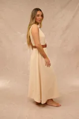 Vestido midi color crudo, sin mangas, con cuello mao y cierre frontal de botones. Incluye un cinturón marrón de cuero sintético con hebilla redonda.