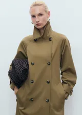 Abrigo tipo trench de diseño recto y oversize, color verde oliva. Presenta cierre de doble botonadura, cuello de solapa ancha, bolsillos laterales y mangas largas con puños abotonados. Incluye forro interior y cinturón desmontable.