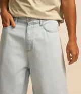 Bermuda baggy de jean color negro con pespuntes contrastantes, cierre de botón y cremallera, y bolsillos.