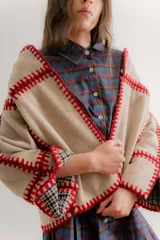 Chaqueta de paño reversible con diseño de cuadros en el interior. Presenta bordes con costuras decorativas en hilo rojo y mangas con puños vueltos que dejan ver el estampado interior.