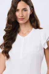 Blusa blanca sin mangas con volados en los hombros, cuello redondo con aberturas y cierre frontal parcial con botones.