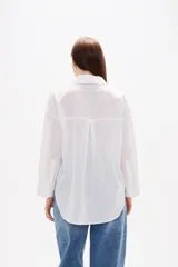 Camisa de algodón blanca, de corte clásico con cuello camisero, cierre frontal con botones, mangas largas con puños y bolsillo frontal en el pecho.