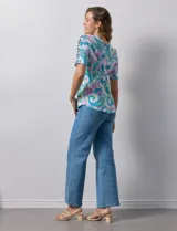 Remera de algodón estampado con diseño paisley en tonos celeste, rosa y amarillo. Tiene cuello redondo y mangas cortas con detalle de entrelazado y aberturas en los hombros.