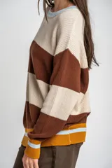 Sweater oversize de tejido de punto con diseño de rayas horizontales anchas en color beige y azul marino, cuello redondo marrón y puños y dobladillo en marrón con líneas beige y blancas.
