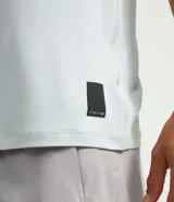 Remera deportiva de hombre con tecnología dry fit, cuello redondo y manga corta. Presenta un diseño liso en color beige con una pequeña etiqueta decorativa en el dobladillo.