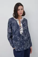 Blusa de manga larga con estampado floral en tonos azul marino y crema. Presenta un escote en V con tapeta abotonada en contraste y un corte holgado.
