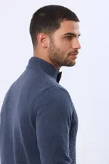 Buzo de punto color beige, con cuello alto y cierre frontal con cremallera y solapa de gamuza con botón. Presenta un tejido texturizado en el cuerpo y mangas lisas.