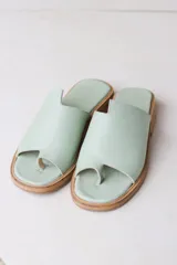 Sandalias de cuero color verde agua, con tira entre los dedos y suela plana color madera.