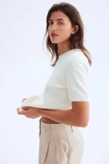 Buzo de punto fino suave con cuello redondo y manga corta. Presenta terminaciones acanaladas en el cuello, puños y bajo.