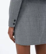 Blazer corto con estampado de pata de gallo en blanco y negro, con cuello solapa, cierre cruzado con botones y bolsillos delanteros simulados.