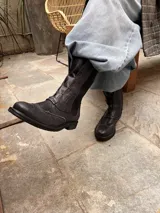 Bota tipo borceguí de cuero color azul noche, con diseño de estilo brogue en la puntera. Presenta elástico lateral, cierre interno y suela de goma con taco bajo.