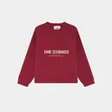 Suéter de punto grueso color bordó con diseño de cuello redondo y mangas largas. Presenta el logo de la marca Eme Studios tejido en técnica jacquard en el frente en color crema.