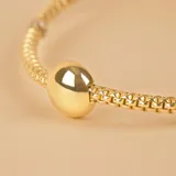 Pulsera extensible de malla en oro 18k, con diseño bicolor en oro amarillo y blanco, y detalle de esfera central pulida.