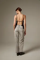 Top halter negro de viscosa, sin mangas, con tirantes finos y cobertura completa de ojalillos metálicos plateados.