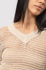 Sweater calado color beige de hilo con escote en V, mangas largas y silueta relaxed.