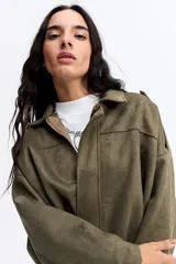 Campera de gamuza sintética color verde oliva, con silueta amplia, hombros caídos y cierre frontal. Presenta un diseño estructurado con volumen en mangas y cuerpo.