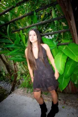 Vestido corto de tela brillante con escote en V profundo, tiras para atar al cuello y detalle de ajuste cruzado debajo del busto. Presenta un diseño entallado en la parte superior y falda con volado en el ruedo.