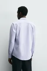 Camisa de manga larga, color celeste con finas rayas verticales blancas, cuello italiano y cierre frontal de botones.