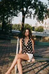 Top negro con estampado de lunares blancos, cuello halter, escote en pico y lazo en la espalda.