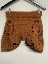 Short tejido a crochet color marrón, con cintura alta y diseño calado en las piernas.