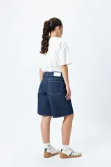 Bermuda de denim color azul oscuro, de corte relajado y largo a la rodilla, con costuras contrastantes en color claro.