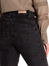 Pantalón de jeans negro de tiro medio, corte skinny, con bolsillos delanteros con cierre y ruedo desflecado.