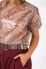 Remera de manga corta con diseño de lentejuelas en color rosado, cuello redondo y ajuste holgado.