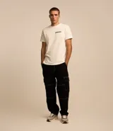 Pantalón masculino modelo baggy confeccionado en sarga de algodón, con cintura con trabillas, bolsillos cargo laterales y costuras con pespuntes en contraste.