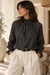 Blusa de seda con diseño de rayas verticales en color negro y blanco, calce holgado, cuello smock fruncido y mangas largas abullonadas con puños elásticos fruncidos.