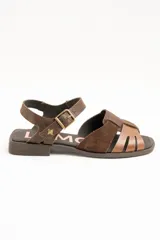 Sandalias de cuero color marrón, estilo romano, con tiras entrelazadas en la parte delantera y tira ajustable al tobillo con hebilla metálica.