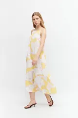 Maxi vestido amarillo con estampado floral blanco y rosa, de tirantes finos y corte holgado.