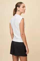 Top de calce entallado, sin mangas y con cuello alto, confeccionado en tejido texturado de líneas simples.