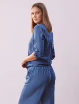 Blusa celeste de tencel, marca Alex & Parker. Cuello a la base, escote en V y abertura central con botones. Delantera con bolsillos. Largo de manga regulable con presilla y botón. Terminación de ruedo con nudo.