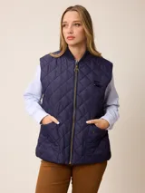 Chaleco acolchado de diseño matelassé con cierre frontal completo, cuello tipo bomber y bolsillos laterales. Presenta un pequeño bordado decorativo en la parte inferior.